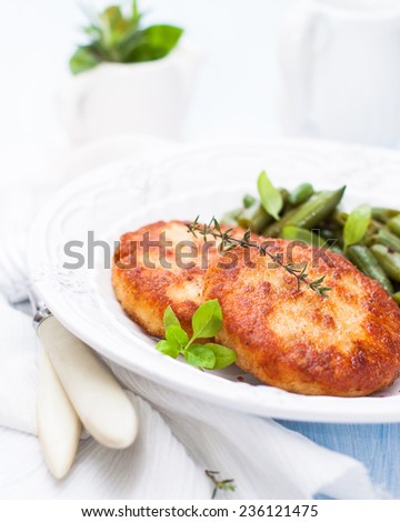 turkey cutlets with a side dish of green beans on a white plate