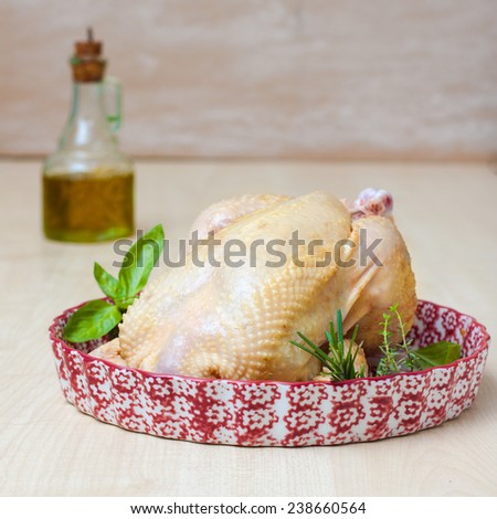 fresh fat chicken with herbs on a plate prepared for roasting