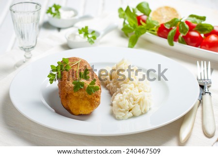 chicken and chicken Kiev with mashed potatoes. Chop chicken fillet stuffed with juicy butter, cheese and greens on a white plate