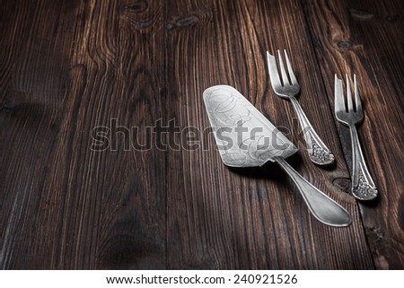 silver cutlery for dessert -  cake spatula and forks on a wooden background