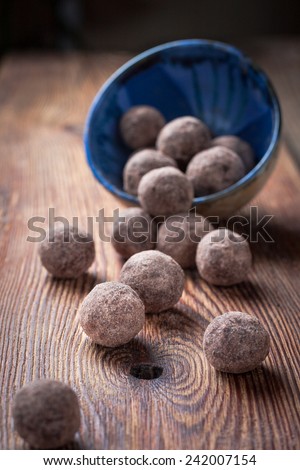 Chocolate truffles with cocoa, nuts, dried fruit, figs and honey for a healthy diet, fasting and vegetarianism in a blue bowl on dark wooden background