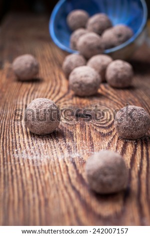 Chocolate truffles with cocoa, nuts, dried fruit, figs and honey for a healthy diet, fasting and vegetarianism in a blue bowl on dark wooden background