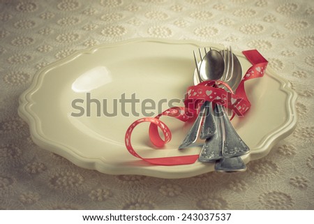 white plate with cutlery, tied with a red ribbon for a romantic dinner couples in love on Valentine\'s Day or wedding