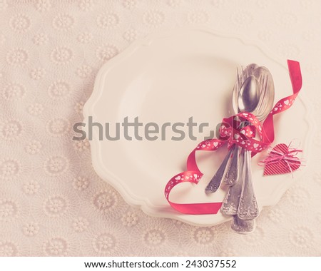 white plate with cutlery, tied with a red ribbon for a romantic dinner couples in love on Valentine\'s Day or wedding