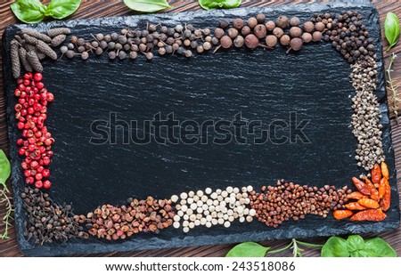 Assorted all kinds of dry pepper on a background of black slate board - chili, grains of paradise, white, Sichuan pepper, Bourbon pepper, pink, long pepper, Cubeb, Javanese pepper, allspice, Monk