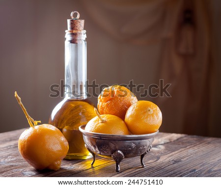 Moroccan pickled lemons in a metal bowl and olive oil in a glass bottle on a wooden background