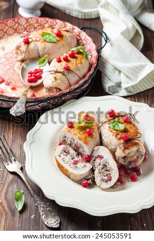roulade of chicken breast with red currants, mushrooms and onions on a white plate on a wooden background