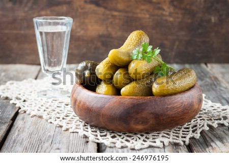 pickles and a glass of vodka on a wooden table