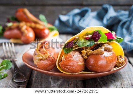 grilled sausages with mustard and lettuce wrapped in a tortilla