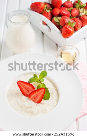 rice milk porridge with strawberries and mint on a white background