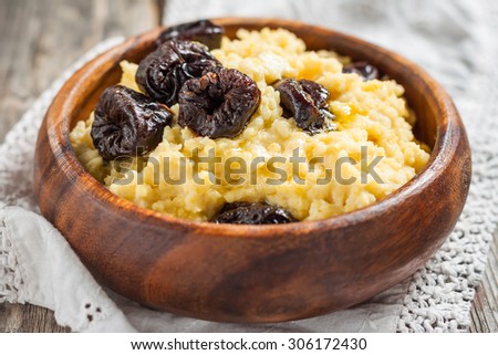 Millet milk porridge with plums on a wooden background. Russian kitchen
