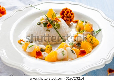 Fish in citrus sauce with rice. Cod with tangerines and marigold flowers