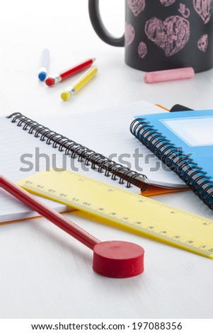 Colorful writing tools (eraser, pencil, ruler, notebook) on young children\'s desk