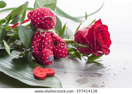 Red rose bouquet with red Teddy bear and heart on wet background.