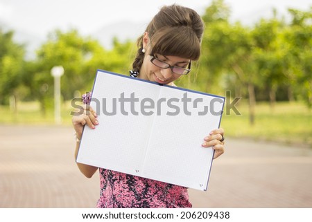 Lovely girl with glasses holding an open notebook. Mixed race  European / Caucasian female student woman looking at notebook.