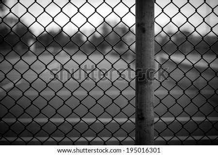 Black and white chain link fence background image with background blurred in a shallow depth of field.