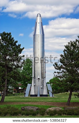 A stainless steel Convair Atlas Rocket (Mercury Program) stands in a field.