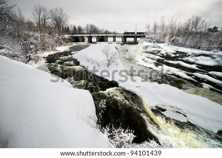 Hog\'s Back falls located on the Rideau River in Hog\'s Back park in Ottawa, Ontario Canada frozen over in winter.
