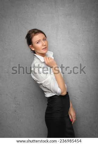 Pretty smiling young woman in office clothes on gray concrete wall. Business concept.