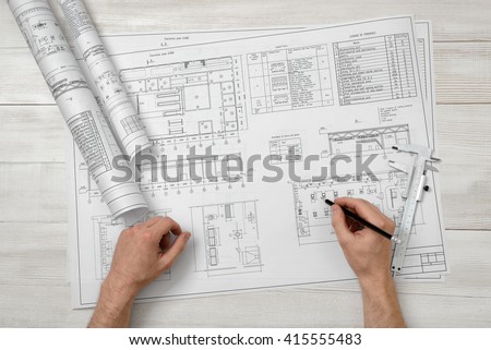 Hands of man holding a pencil over drawing layout in top view.  Workplace of architect or constructor. Engineering work. Construction and architecture. Architect drawing. Exact calculation.