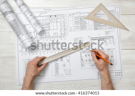 Close-up of architect hands holding centimeter ruler and pencil. Measuring process. Work place of draftsman, architect, constructor. Working process. Engineering work. Construction and architecture