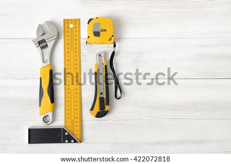 Building tools including centimeter ruler, wrench and cutter placed in the right side on wooden surface with open space. Top view composition. Measurement. Fixing and cropping. Hand tool. Tools for