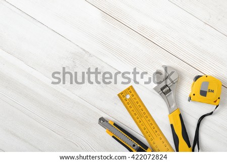 Construction tools including centimeter ruler, wrench and cutter placed in the right down corner on wooden surface with open space. Top view composition. Measurement. Fixing and cropping. Hand tool