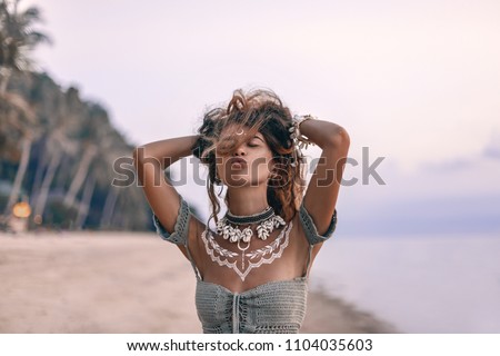 young beautiful boho woman sending air kiss on the beach at sunset