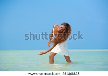 Beautiful girl in white dress walk on the water on tropic beach in Phangan