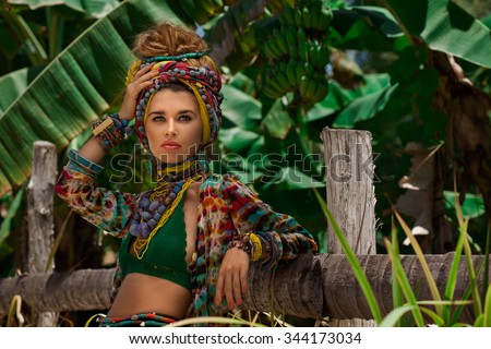 Fashion model in turban posing outdoors with jungle background