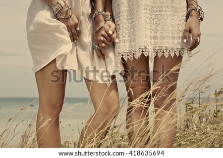 close up of women`s legs in boho style white dresses