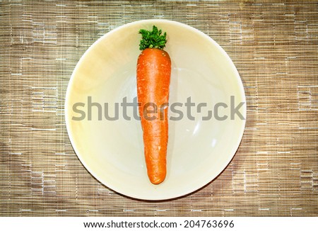 One of carrot in the dish above brown synthetic fabric background