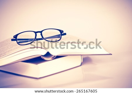 black rimmed glasses placed on the opened book