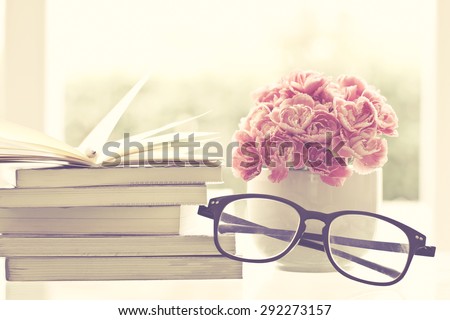 the fresh pink carnation flower with books and old glasses background