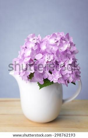 selective focus of the sweet purple  hydrangea flowers in white vase on wooden plate , vintage and still life