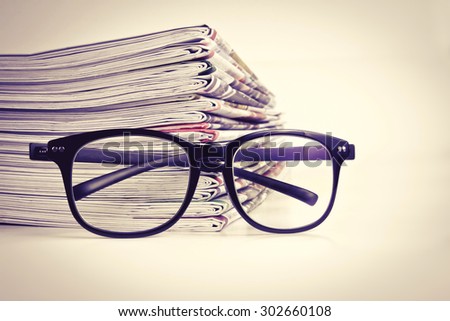 selective focus on reading eyeglasses with stacking of the newspaper background ,business information concept