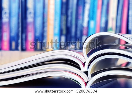 close up stacking of opened magazine with blurry bookshelf background , extremely shallow DOF
