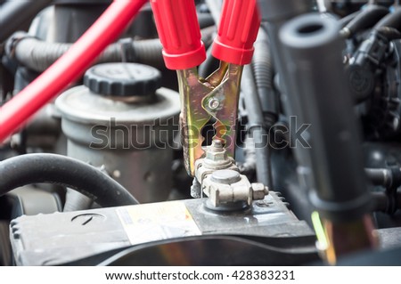 red clamp on car battery. for charging battery car with electricity. selective focus at between red clamp and  battery pole