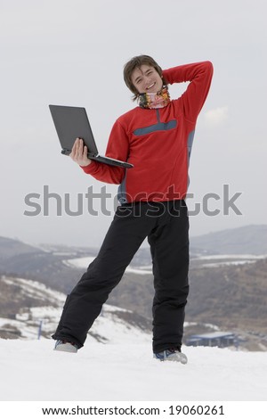 Happy teens student with laptop in hand in winter mountains Tien Shan over sky