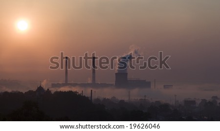 Smoke from factory over city in sunrise