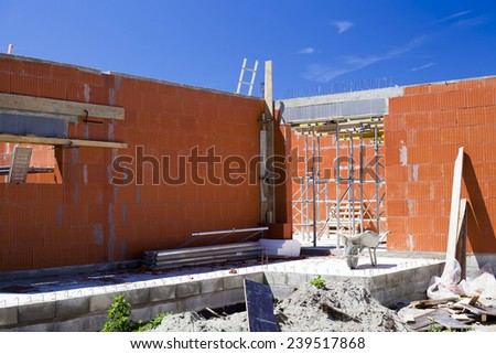 Construction work. Building of red brick cottage on blue sky background