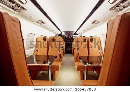 Private plane interior with wooden tables and leather seats