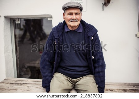 ALBEROBELLO, ITALY - OCTOBER 31, 2013: Old man sitting on a bench in Alberobello on October 31, 2013, Italy