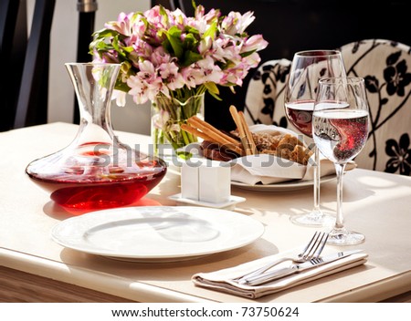 Fine restaurant dinner table place setting: napkin, wineglass, plate, bread and flowers