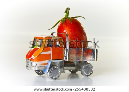 Small lorry loaded with one big red tomato - concept image