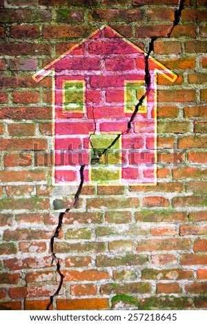 Cracked brick wall with a colored house drawn on it