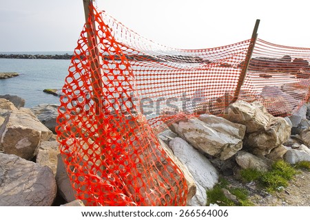 Construction site with safety orange grid at the seaside