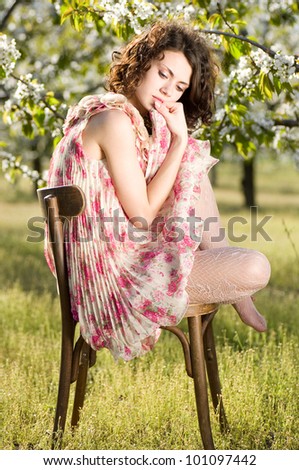 Beautiful woman sits on a chair in a spring garden