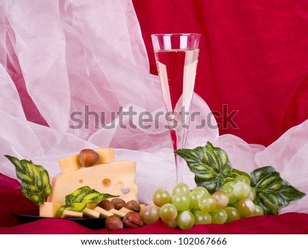 Beautiful composition with wine, grape, cheese and long loaf on red background
