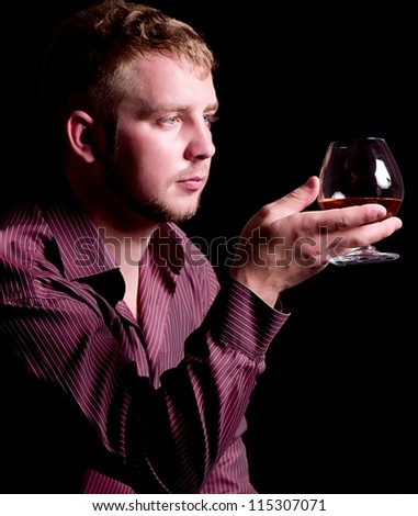 Young man with brandy glass on black background